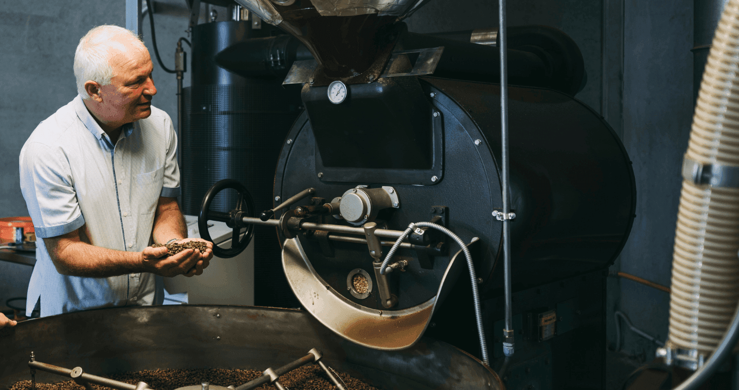A man at a coffee roaster holding freshly roasted coffee beans