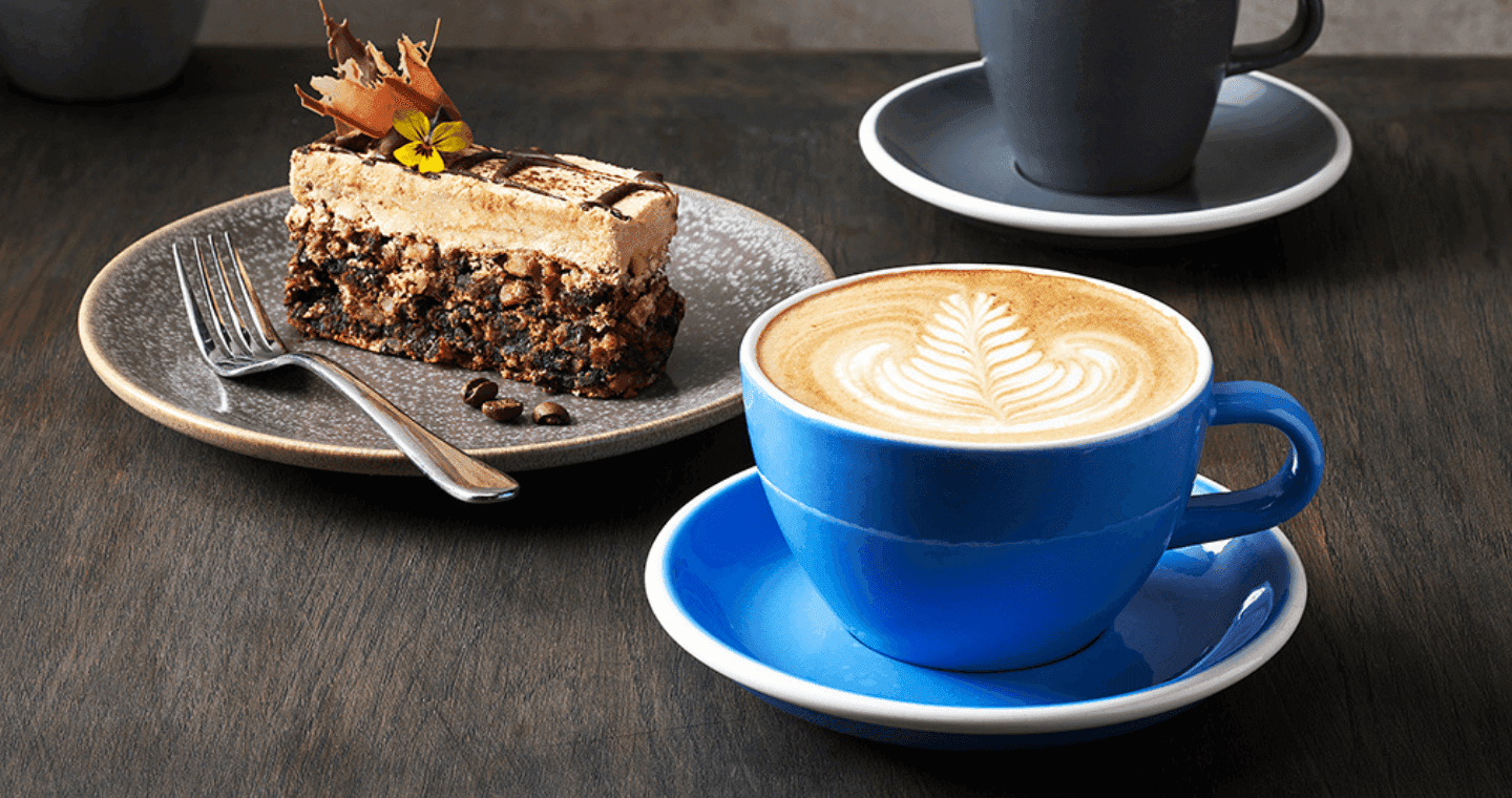 A blue coffee cup and a slice with a fork next to it